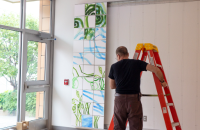 Artist Daniel Kohn applies colorful tiles on the walls in Lancaster General Health's Proton Therapy Center